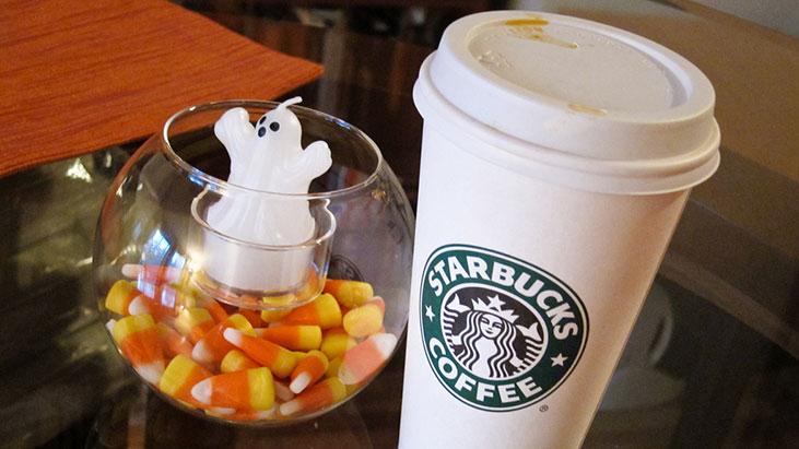 A Starbucks Halloween cup adorned with spooky graphics, promoting the new Starbucks Partner Benefits for 2025.